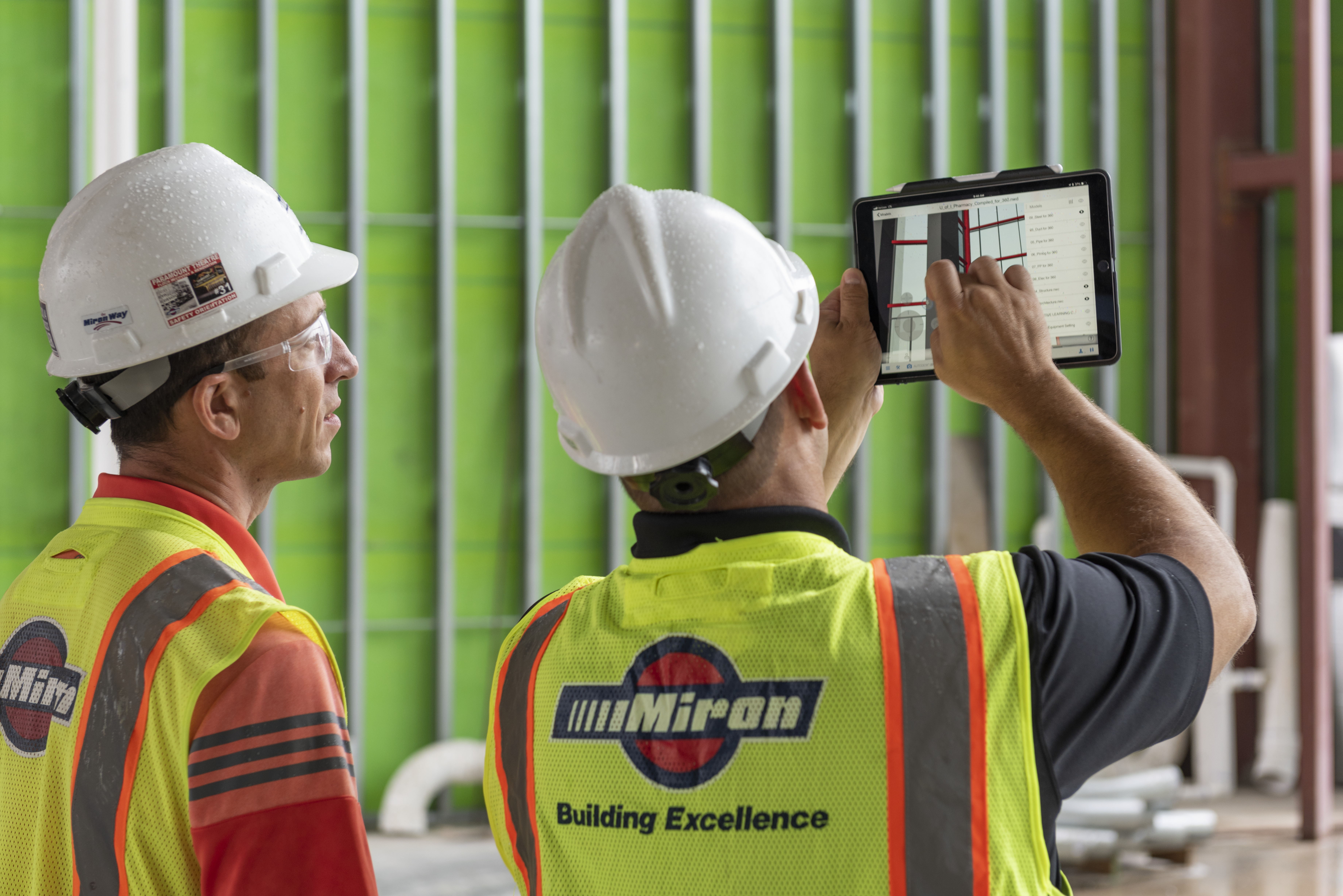 Twee bouwkundigen kijkend naar een tablet op de bouwplaats